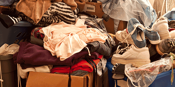 Image of hoarding situation featuring clothing, boxes, and trash many property management companies must face.